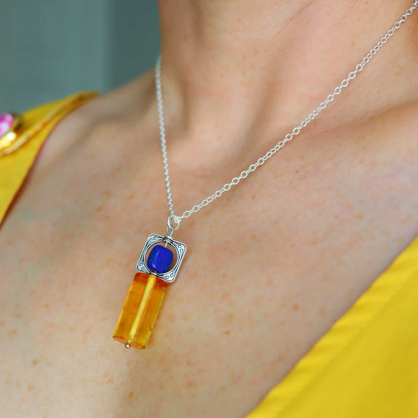 Model wearing lapis lazuli and amber pendant necklace, showcasing natural stone colors and 16-inch chain length.