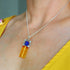 Model wearing lapis lazuli and amber pendant necklace, showcasing natural stone colors and 16-inch chain length.