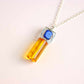 Angled view of lapis lazuli and amber pendant necklace showing gemstone texture, silver-plated setting, and chain detail.