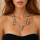 raven skull necklace worn by a person against a neutral background