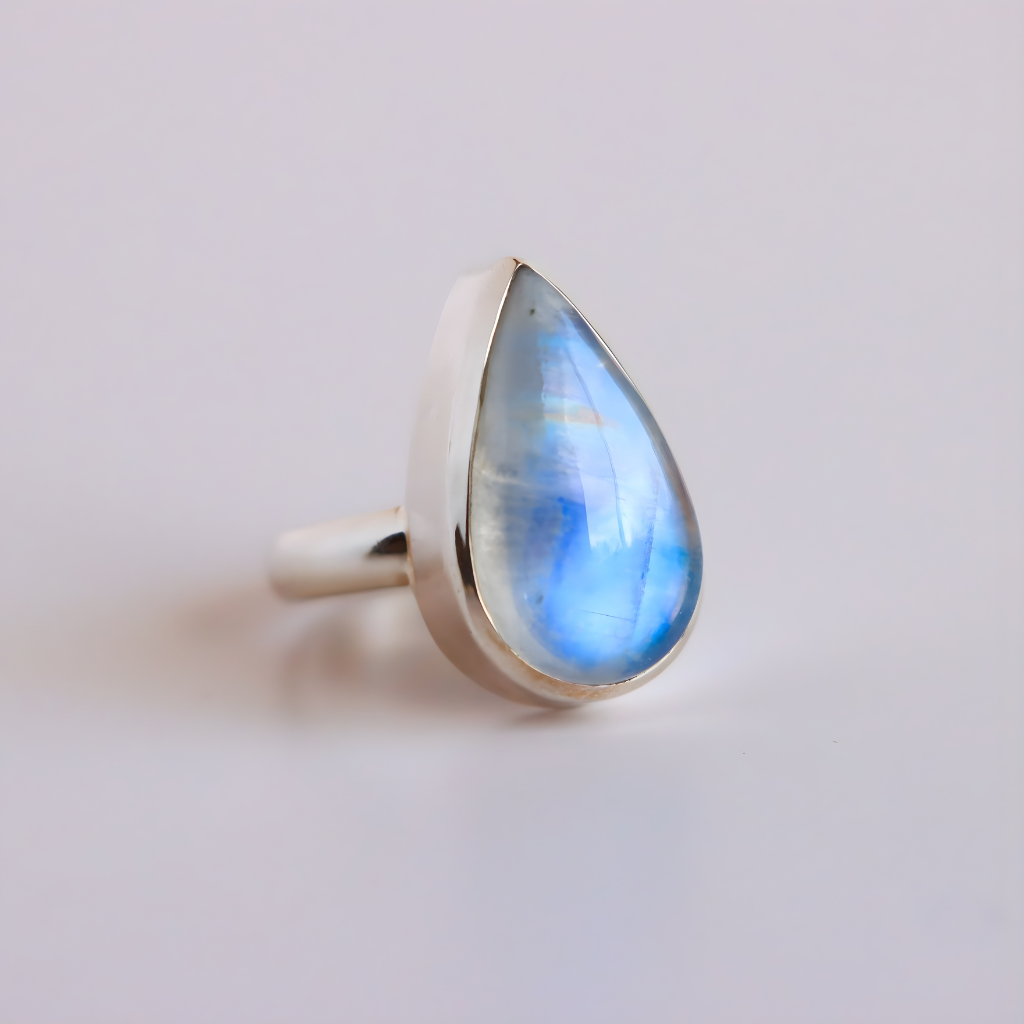 Teardrop-shaped blue moonstone ring on a light gray background