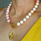 Queen Conch and gold beaded statement necklace with pink and white beads, freshwater pearls, and a hammered gold pendant with front toggle clasp.