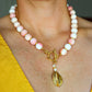 Close-up of a 16-inch handmade Queen Conch and gold beaded statement necklace featuring pink and white conch beads, freshwater pearls, and a hammered gold pendant with a front toggle clasp.