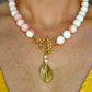 Close-up of a handmade Queen Conch and gold beaded statement necklace with a hammered gold pendant and front-facing toggle clasp worn on a collarbone.