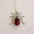 Silver scarab amber pendant shaped like a beetle with a red stone on a light gray background