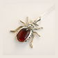 scarab shaped amber pendant with a red stone on a white background