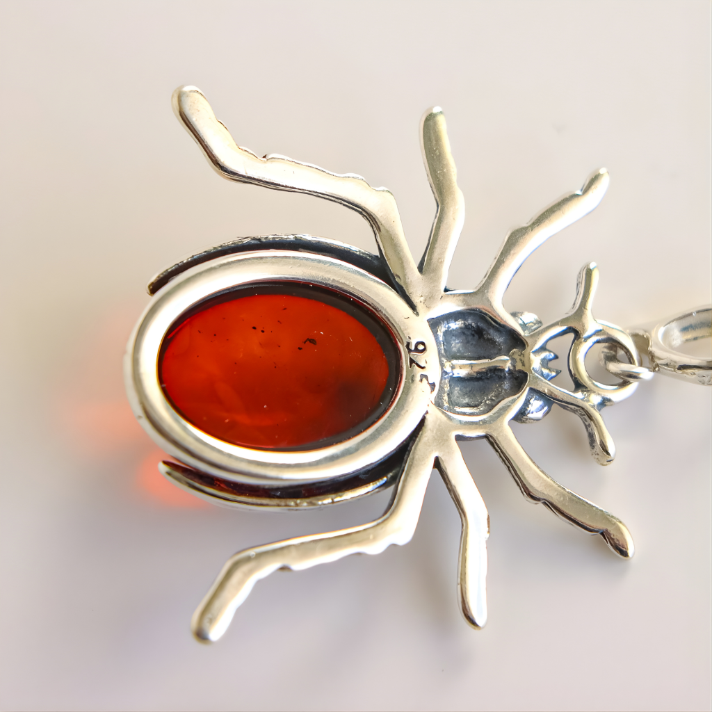 Silver scarab amber pendant with a red stone on a light gray background