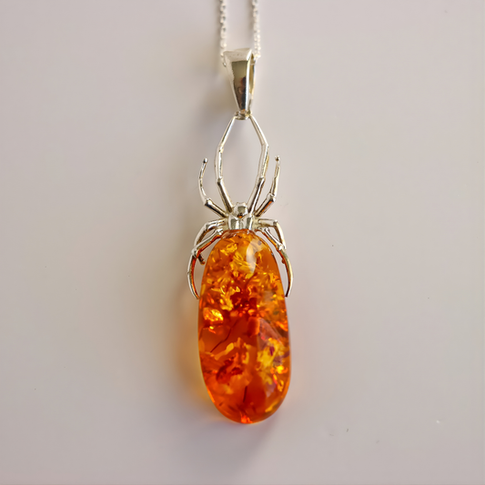 Amber necklace with silver spider pendant  on a light gray background