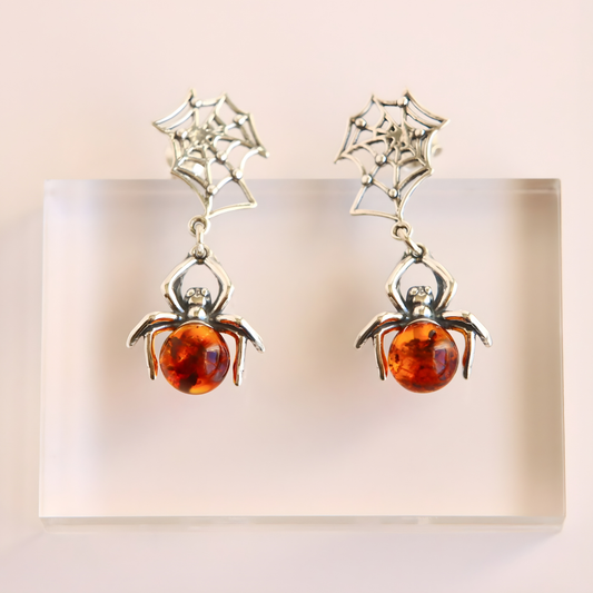 Spider amber earrings with amber stones on a light background