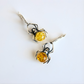 Spider-shaped amber earrings with amber stones on a white background