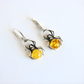 Spider-shaped amber earrings with yellow gemstones on a white background