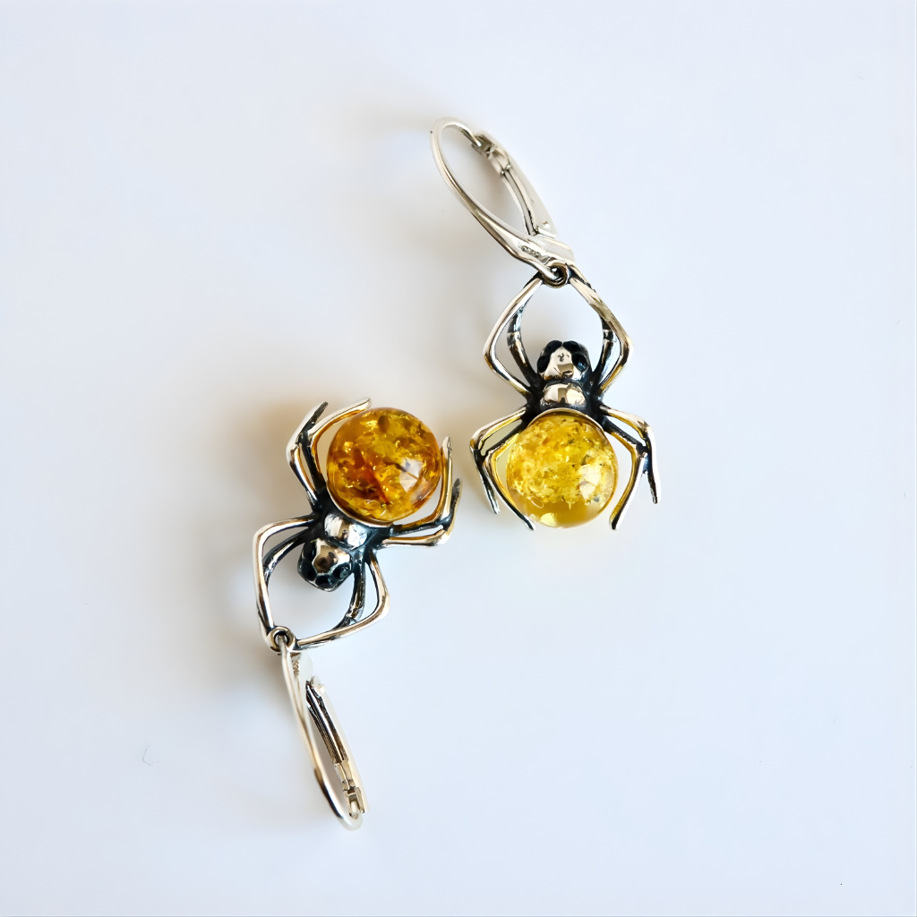 Spider-shaped amber earrings with amber stones on a white background