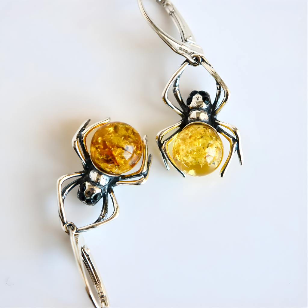 Spider-shaped amber earrings with amber-colored centers on a white background