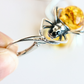Silver amber earrings with a yellow gemstone held by a hand on a white background