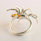 Silver spider statement ring with a red gemstone on a light gray background