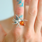 Silver spider statement ring with a amber stone on a finger