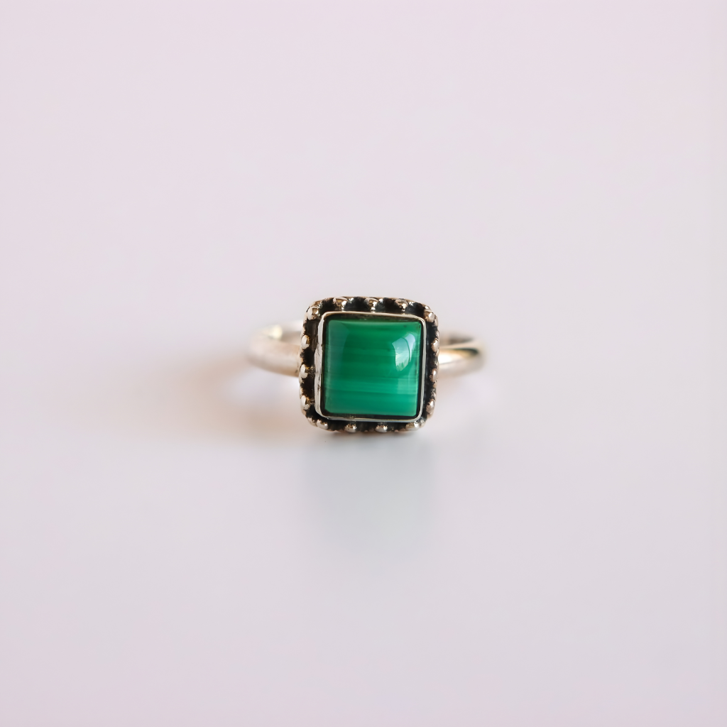 malachite ring with a green gemstone on a light gray background