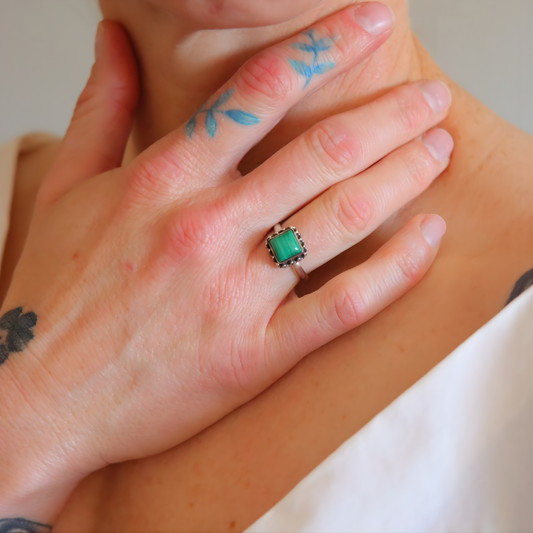 Hand wearing a green malachite ring with a white background