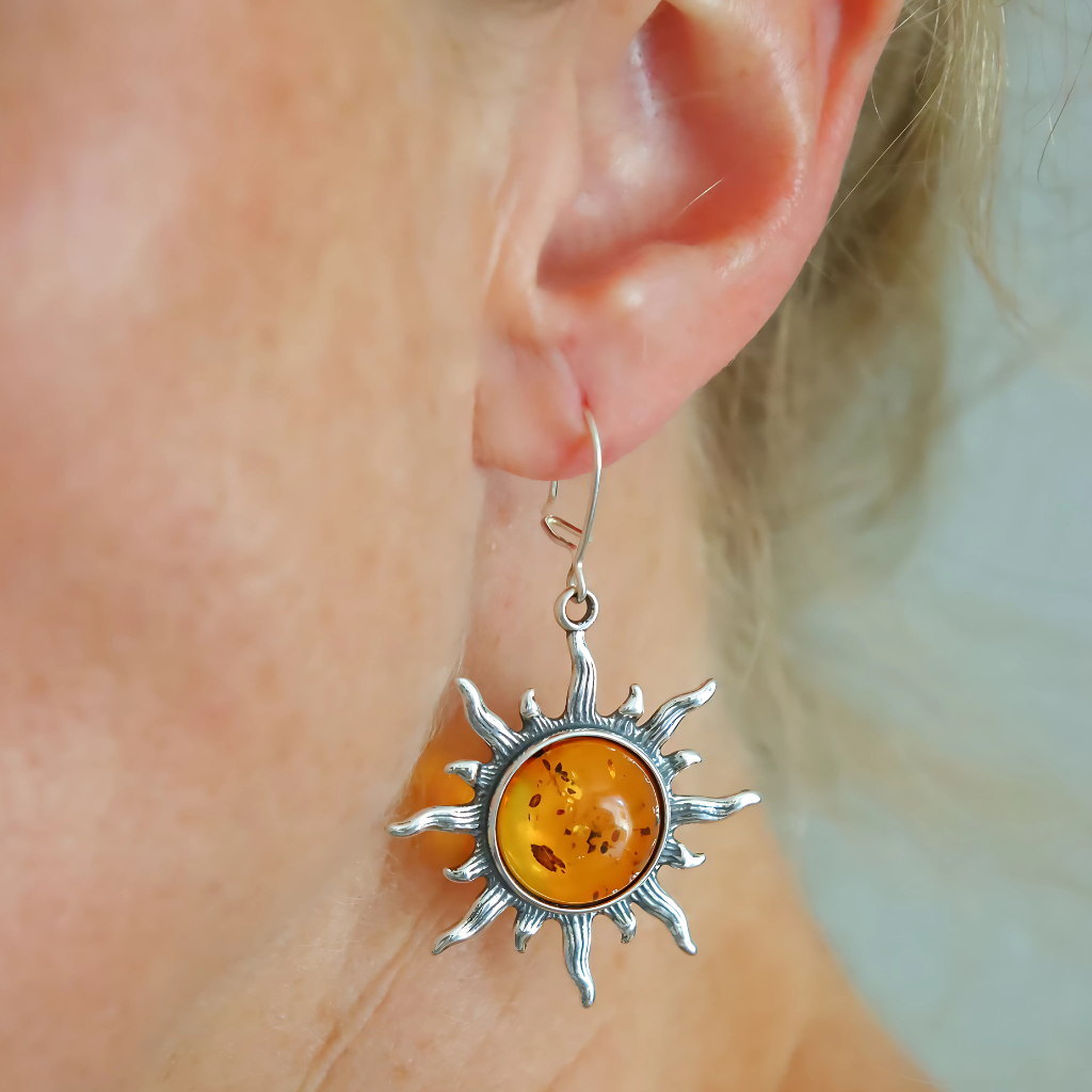 sun shaped sterling silver earrings worn on ear