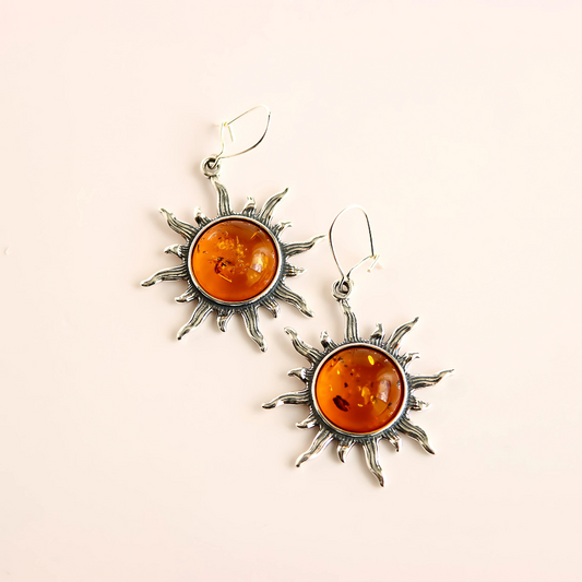 sun sterling silver earrings stacked on beige background