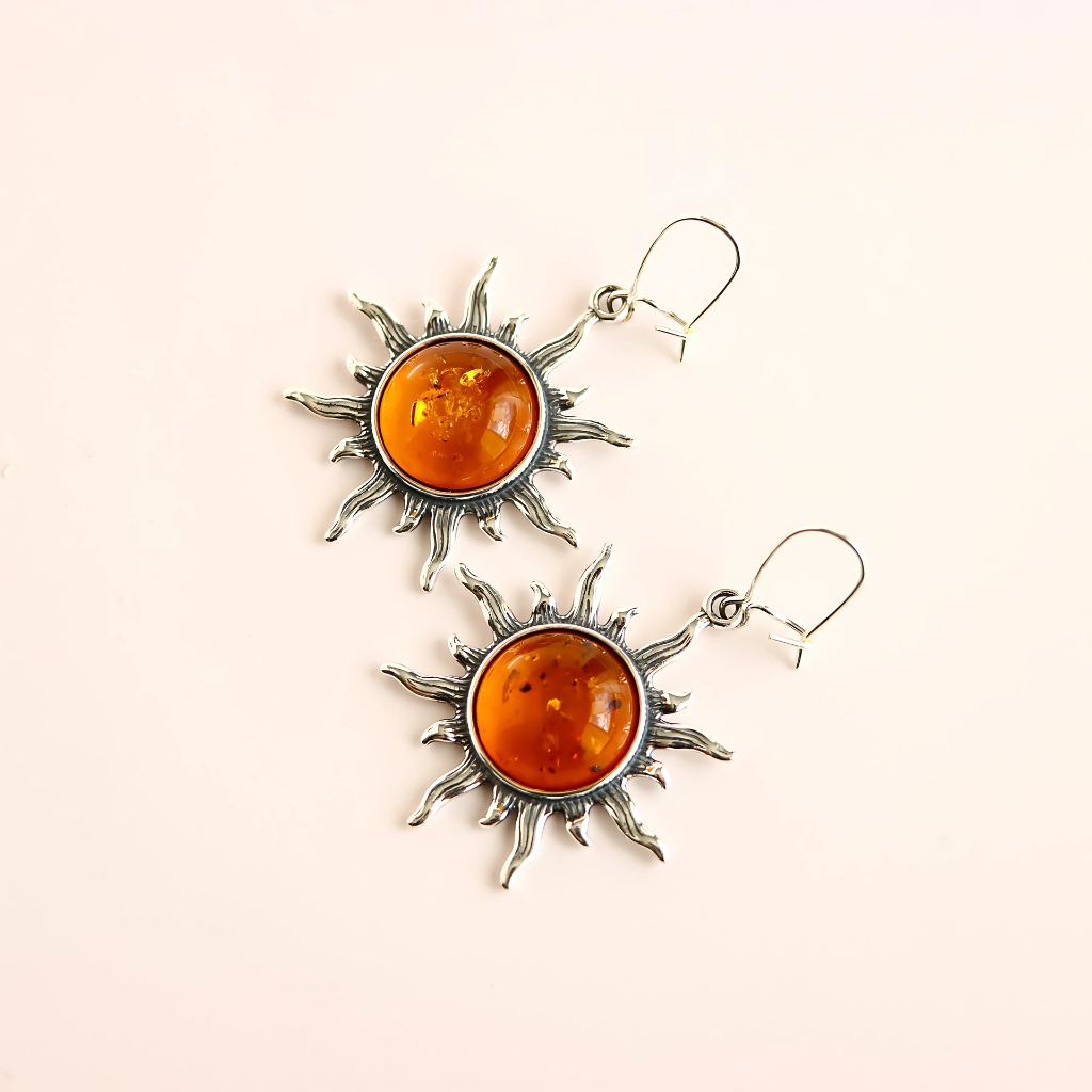 sun sterling silver earrings on side angle with beige background