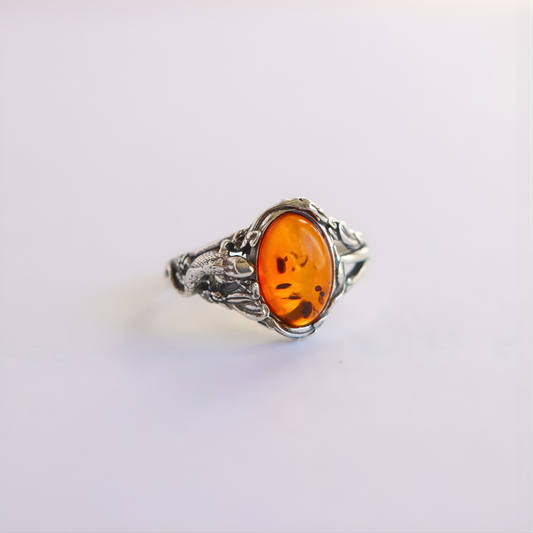 Silver amber ring with an amber stone on a light purple background