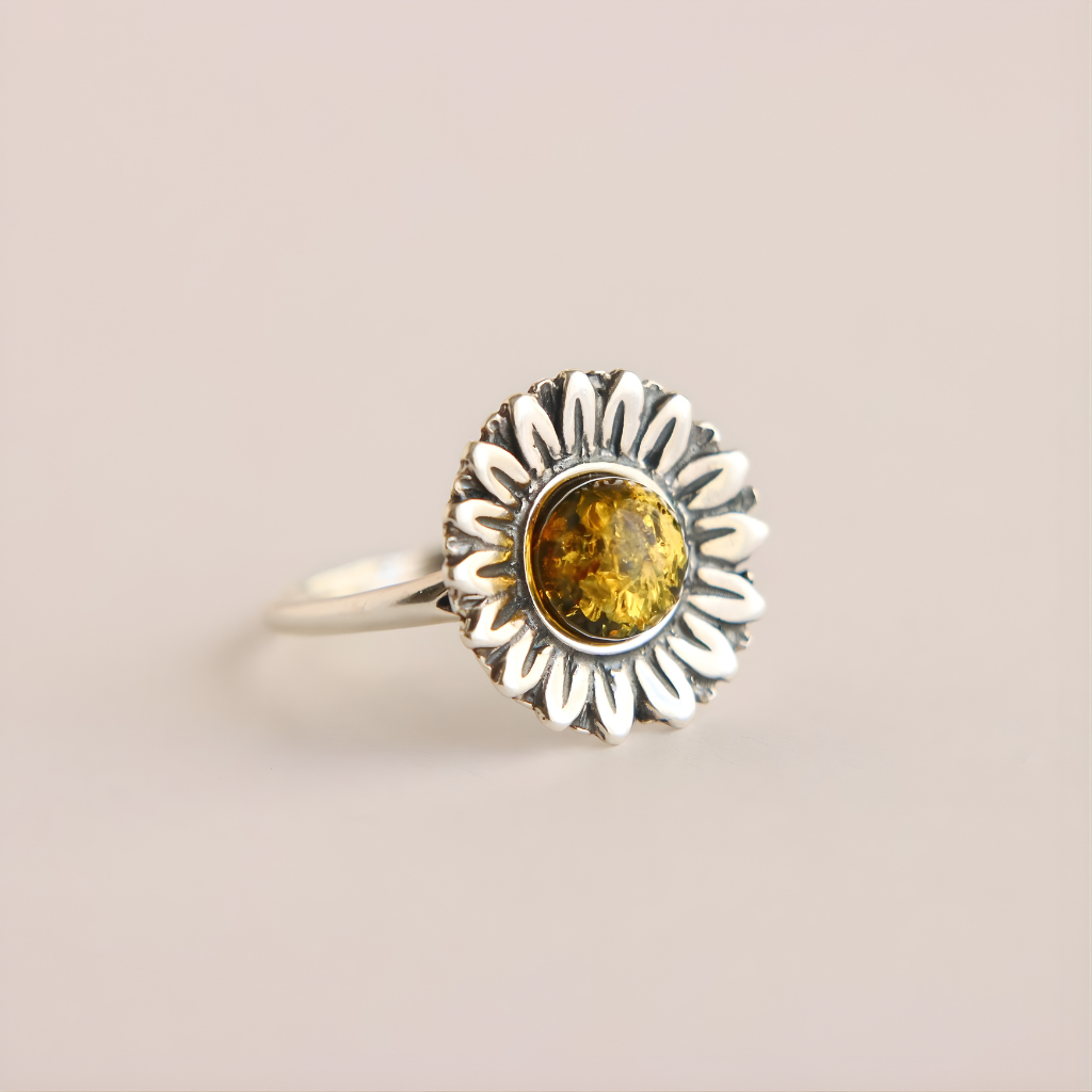 Silver green amber ring with a sunflower design and amber stone on a beige background