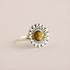 Silver green amber ring with a sunflower design and amber stone on a beige background