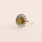 Silver green amber ring with a sunflower design and embedded amber stone on a beige background