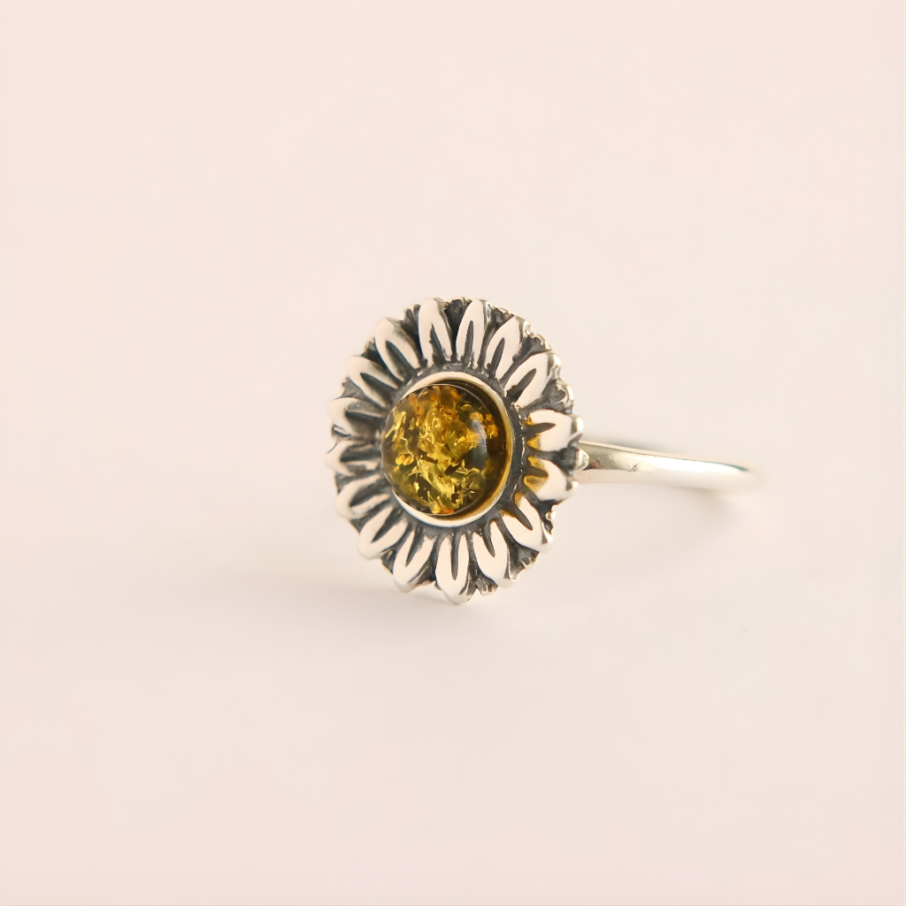 Silver green amber ring with a sunflower design and embedded amber stone on a beige background