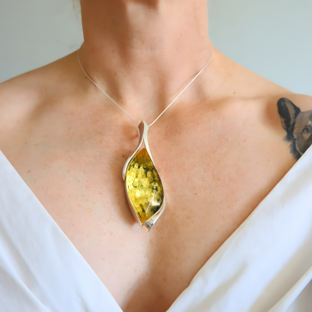 Amber Necklace with a yellow pendant worn by a person against a neutral background