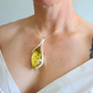 amber Necklace with a yellow pendant worn by a person against a neutral background