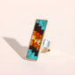 Colorful mosaic amber ring with a silver band on a light background