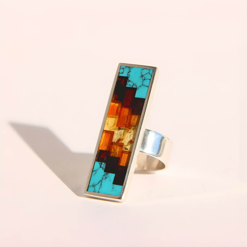 Colorful mosaic amber ring with a silver band on a light background