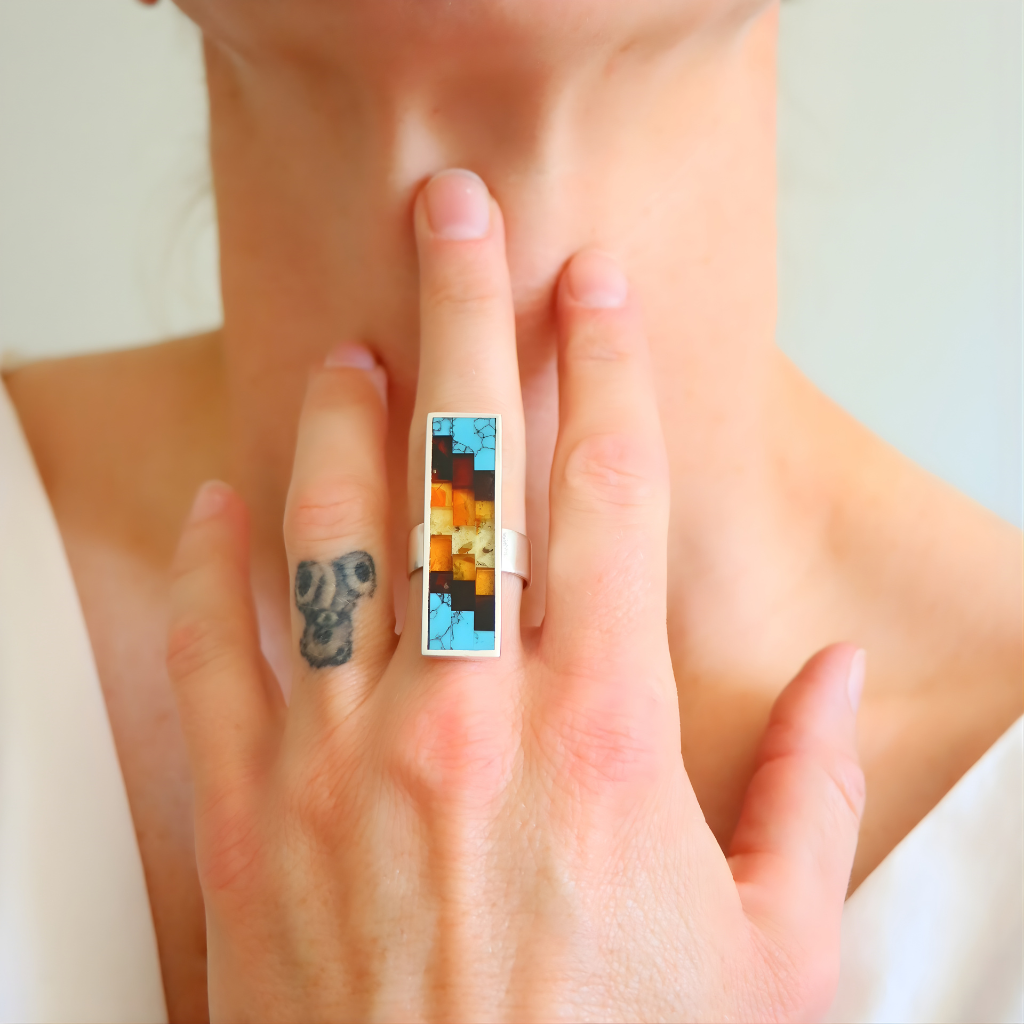 Close-up of a hand wearing a colorful amber ring with a white band.