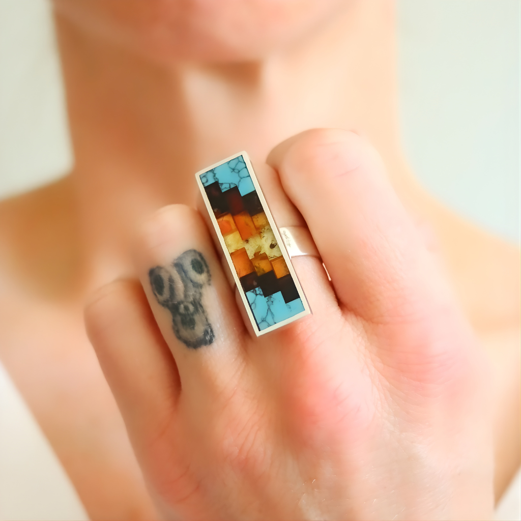 Colorful rectangular amber ring on finger with a blurred background