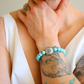 Turquoise beaded howlite bracelet with silver clasp on a wrist with tattoos