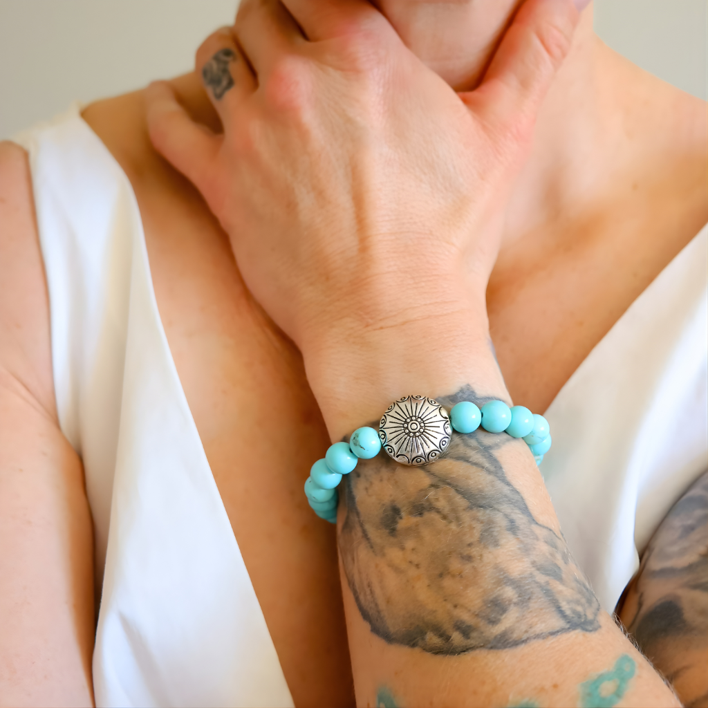 Turquoise beaded howlite bracelet with silver clasp on a wrist with tattoos