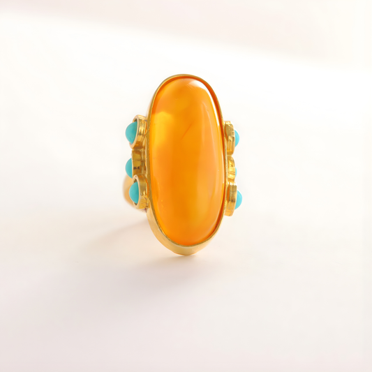 amber Ring with a large orange stone and smaller turquoise stones on a light background