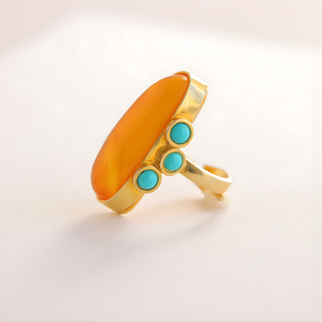 Gold amber ring with orange stone and turquoise beads on a light background