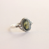 Silver amber ring with a green gemstone on a light beige background