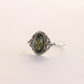 Silver amber ring with a green gemstone on a light beige background