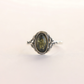 Silver amber ring with a dark stone on a light beige background