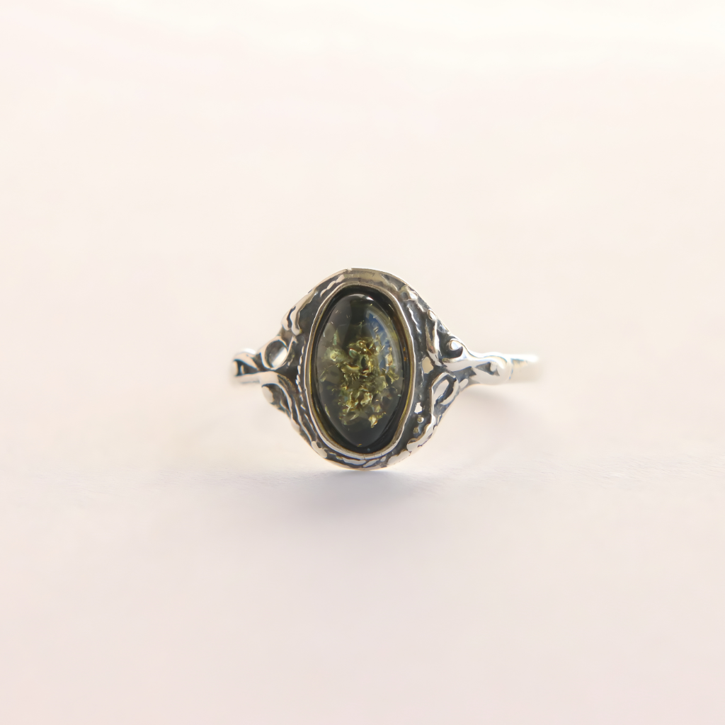Silver amber ring with a dark stone on a light beige background