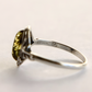 Silver amber ring with a green gemstone on a light background