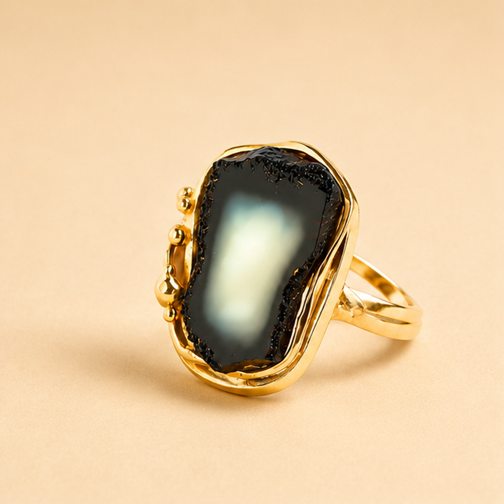 Gold amber ring with a black stone on a beige background