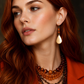 gold drop earrings with amber gemstone on model with red hair on black background