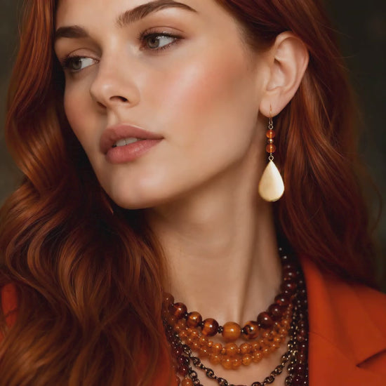 gold drop amber earrings on model on dark background
