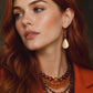 gold drop amber earrings on model on dark background