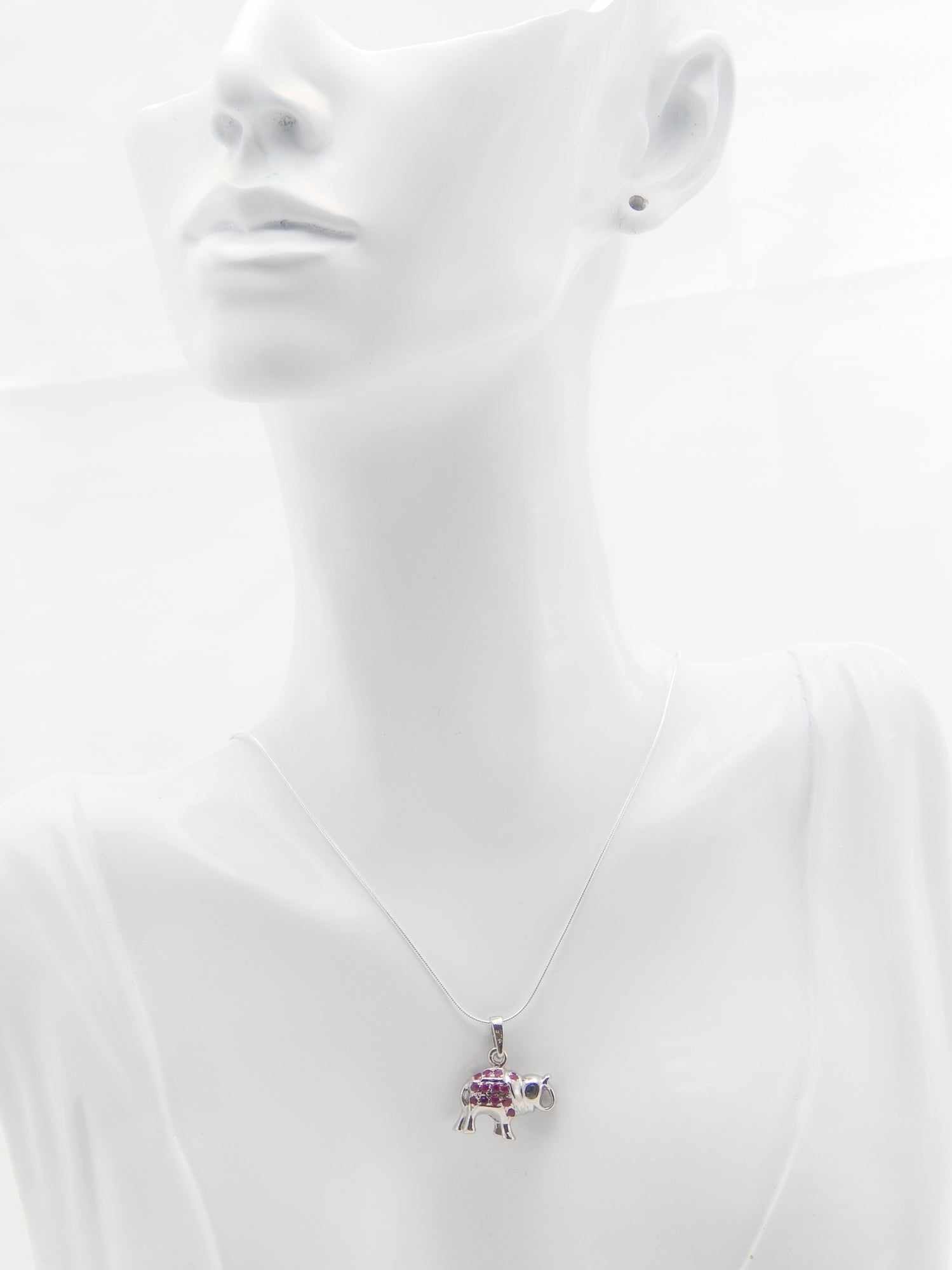 Genuine ruby and sapphire happy elephant necklace in 925 sterling silver displayed on a mannequin.